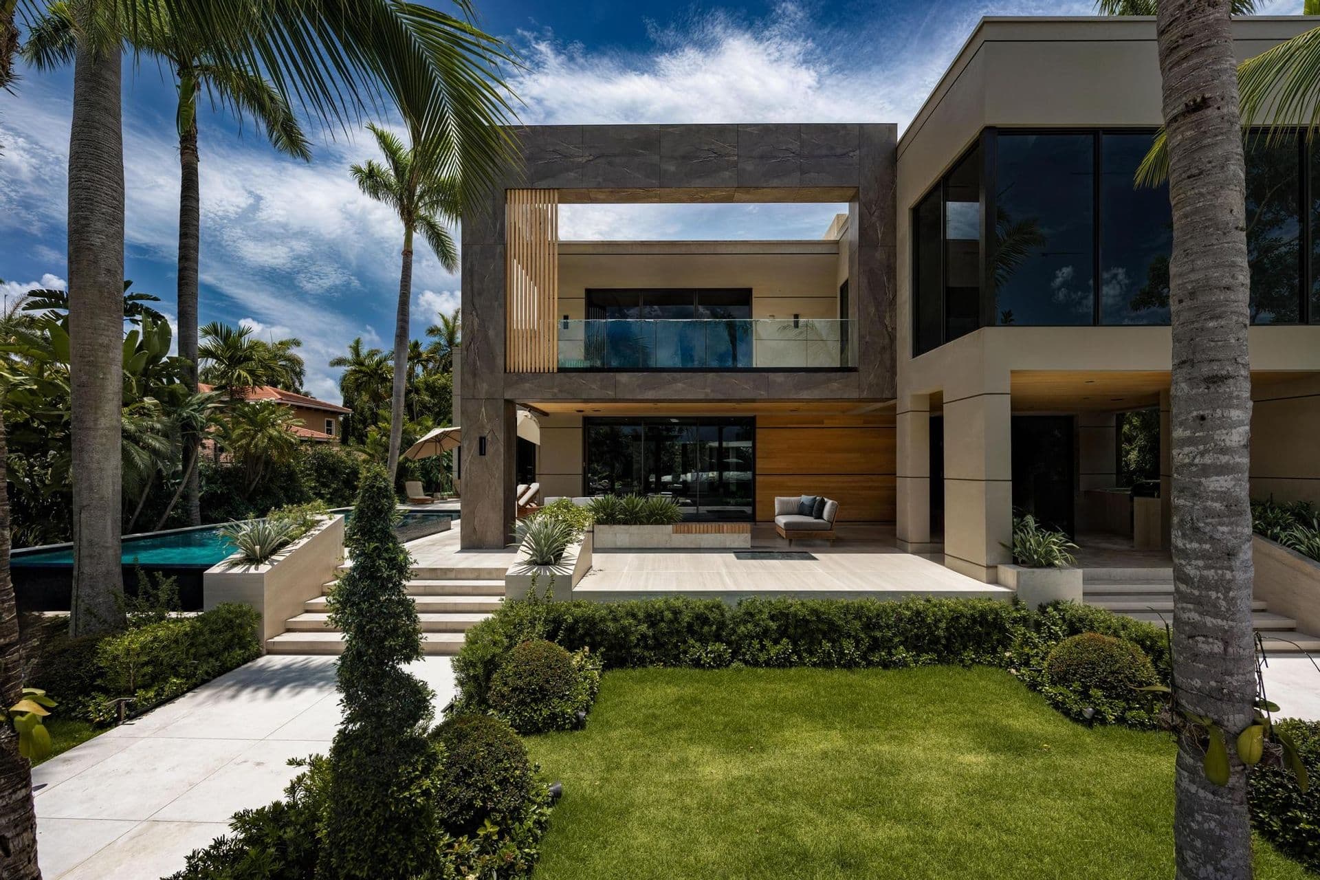 Modern two-story house with wood-toned exterior accents, large windows and palms